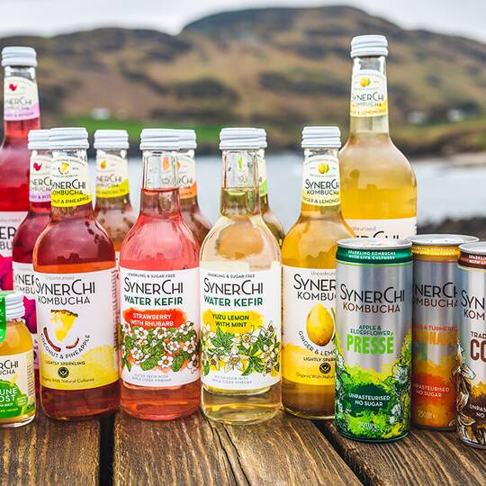 Synerchi Kombucha product range displayed on wooden surface with Donegal landscape backdrop
